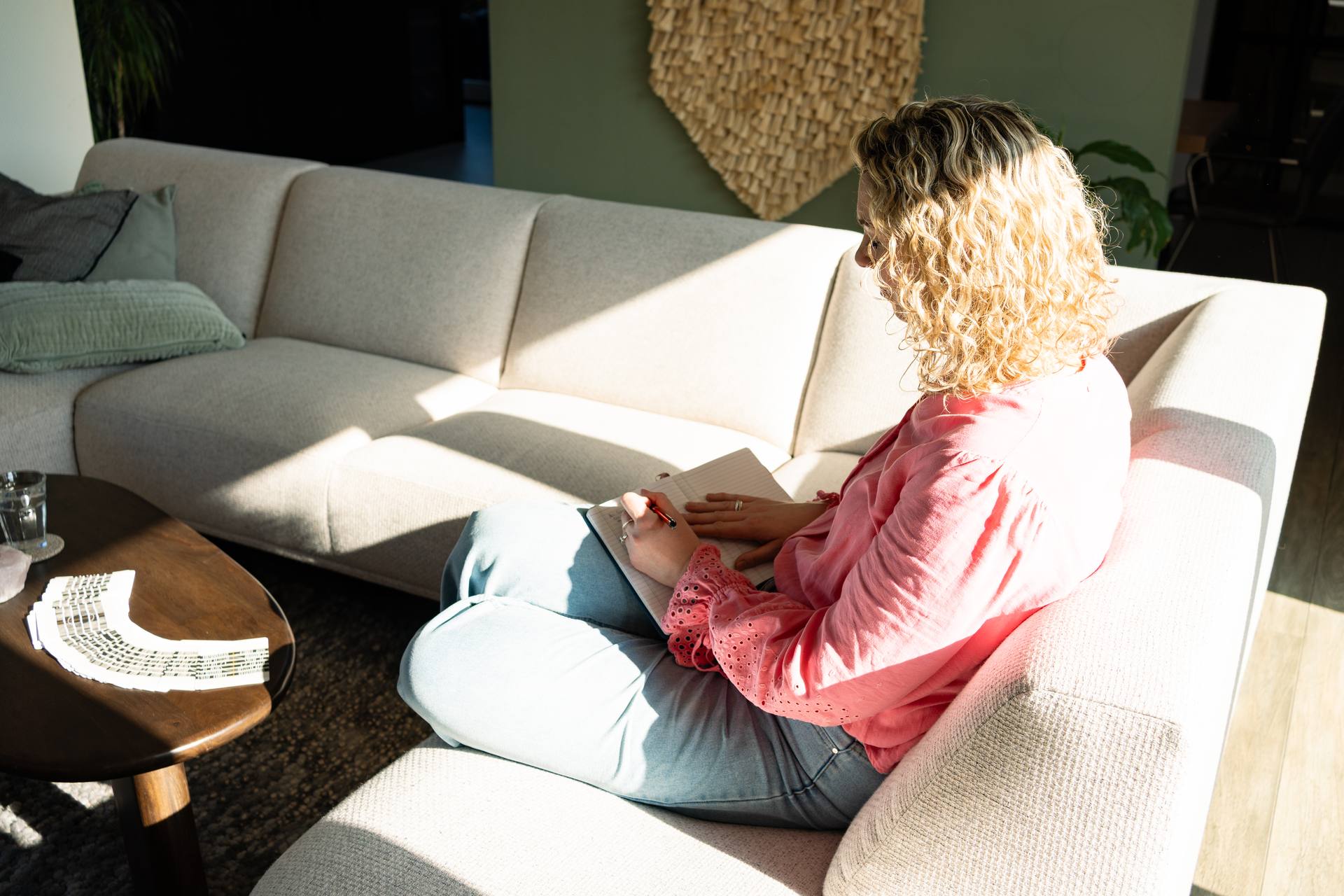 Anniek schrijft in haar journal op de bank in zacht zonlicht